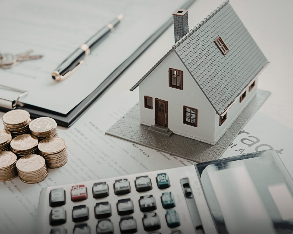 lose-up of a calculator, a set of house keys, and a pen on top of a mortgage application document.