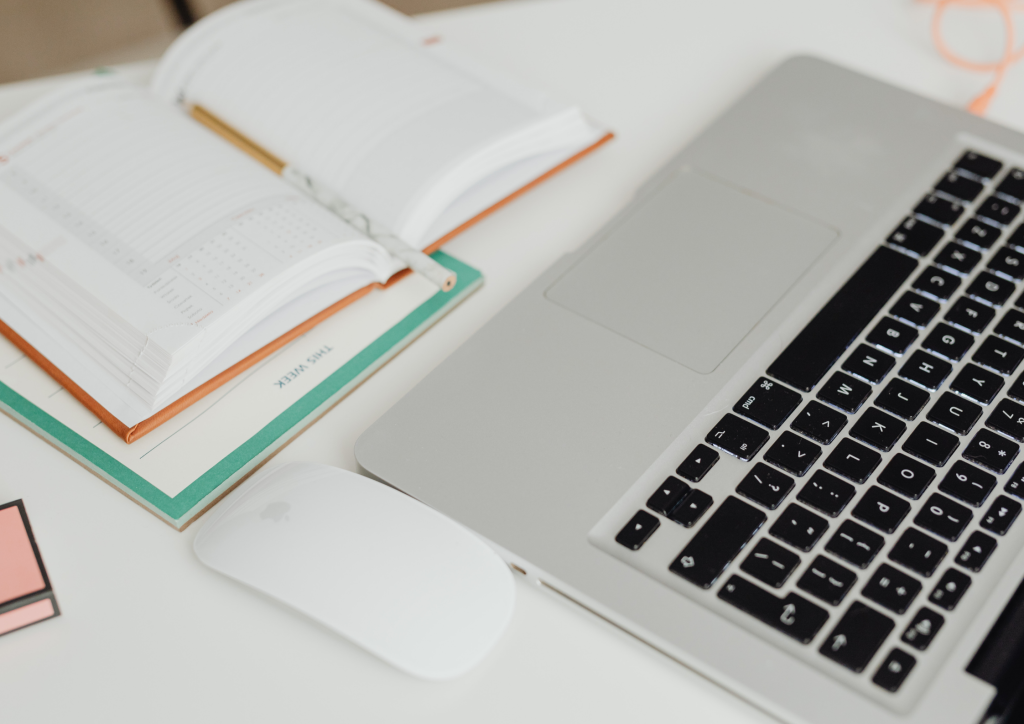 A modern workspace with a laptop, planner, and mouse, representing the strategic financial planning required for a successful home sale.